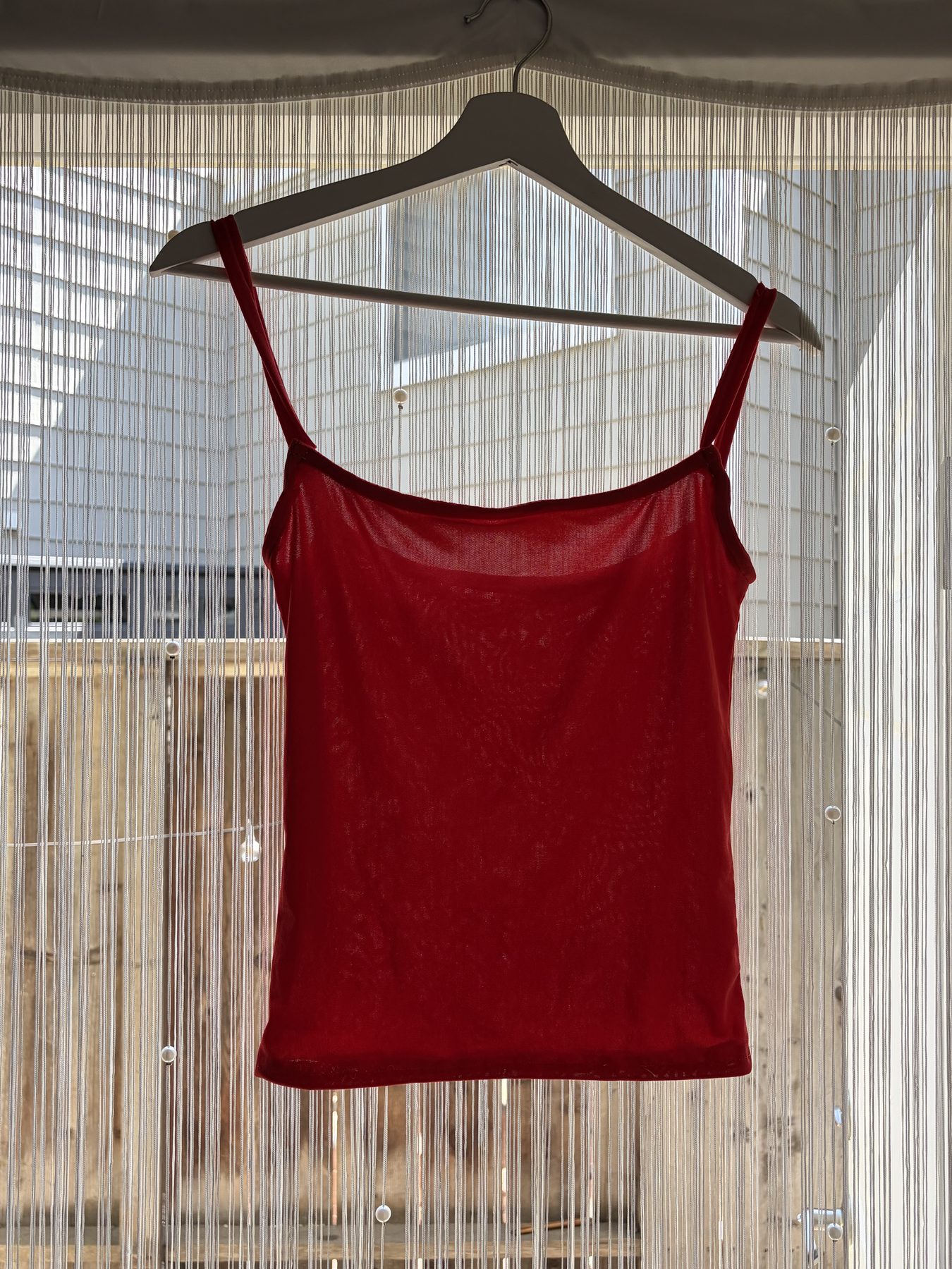 Finished red tank top hanging on a hanger, front view